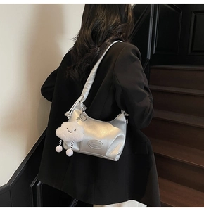 Silver crescent shoulder bag with metallic texture, broad strap, and white cloud charm