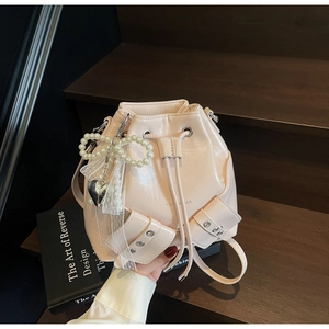 Détail du sac seau à cordon rose avec nœud perlé, rubans en dentelle et pendentif cœur