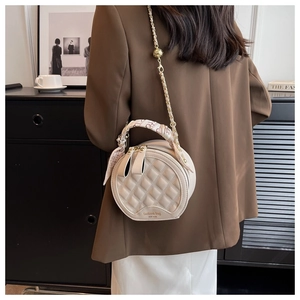 Détail du sac à bandoulière rond matelassé beige avec chaîne et poignée en foulard de soie