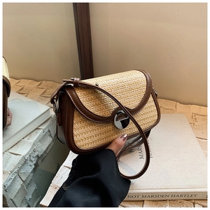 Détail de la texture en paille beige avec bordure en cuir marron et fermoir rotatif argenté