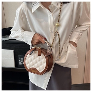 Détail du sac rond matelassé avec poignée en foulard et bandoulière en chaîne dorée