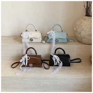 Detail view of four elegant PU leather handbags with pearl charms and lace bows