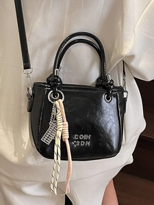 Klassische schwarze Eimertasche aus Kunstleder mit Glanzoptik und Dekofiguren