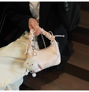 Detail of pink pleated handbag with silver chain strap and white cloud plush charm