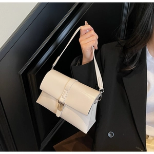 Detail of minimalist cream oil-wax leather shoulder bag with gold buckle hardware