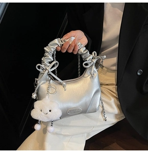 Detail of silver metallic hobo bag with cloud handle, metal chain, and plush charm