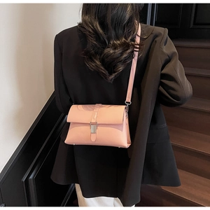 Pink lychee grain leather crossbody bag styled on a model in a minimal indoor setting