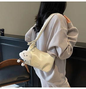 Detail of cream white pleated hobo bag with thick padded strap and plush cloud charm