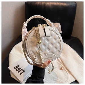 Detail of quilted leather round bag with silk scarf handle and chain strap