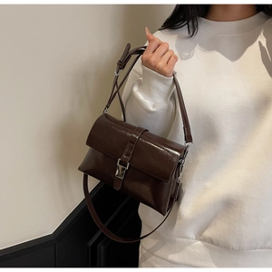 Detail view of deep brown oil wax leather shoulder bag with metallic silver buckle
