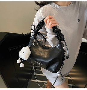 Detail of black pleated hobo bag featuring silver chain strap and plush cloud charm