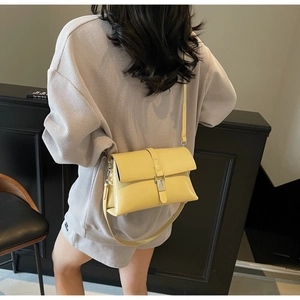 Detail of a creamy yellow vintage oil wax leather shoulder bag with a metal buckle clasp