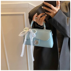 Detail of light blue PU leather handbag featuring a white lace bow and pearl charm
