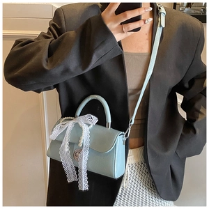 Detail of light blue PU handbag featuring white lace bow and pearl charm decoration