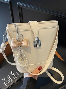 Borsa a secchiello minimalista in pelle beige con chiusura metallica e ciondolo