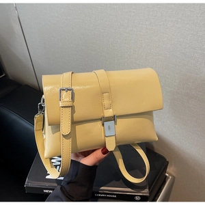 Detail showing the glossy oil wax leather finish and silver buckles of this yellow handbag