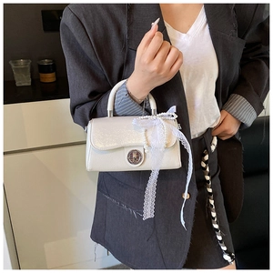 Chic off-white square handbag with pearl charm and lace bow shown on a grey suit model