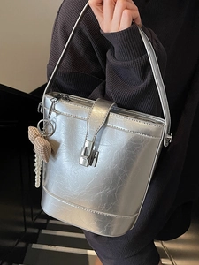 Borsa a secchiello argento minimalista con ciondolo di perle e texture indossata da modella