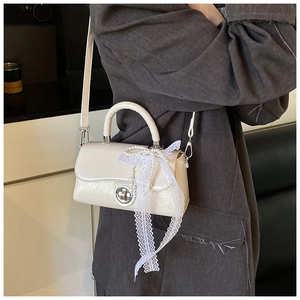 Detail of off-white PU leather crossbody bag with lace and pearl charm on gray blazer