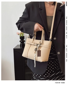Close-up of beige lychee grain leather bucket bag with silk scarf and chocolate charm
