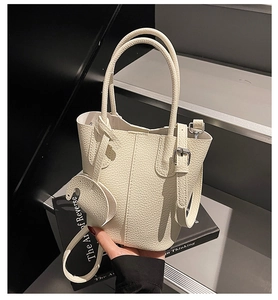 Dettaglio della borsa a secchiello in pelle beige martellata con ciondolo elefante