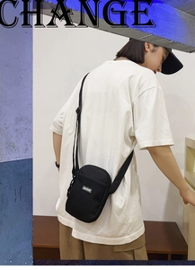 Detail of minimalist black nylon mini crossbody bag with adjustable strap and logo tag
