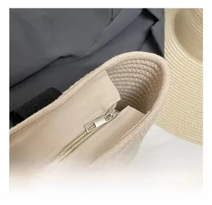 Detalle del bolso de paja tejida con cremallera de metal plateado y asa de cinta negra