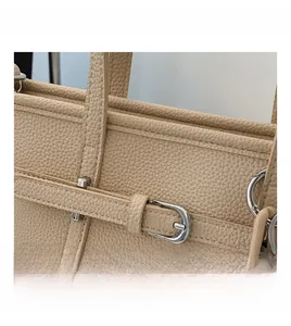 Detail of lychee textured leather bucket bag with metal buckle and resin chain strap