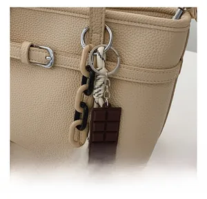 Detail showing the chocolate charm and woven chain on the lychee textured handbag