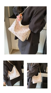 Detalle del estampado de perro de dibujos y el lazo rosa en el bolso de cuero crema
