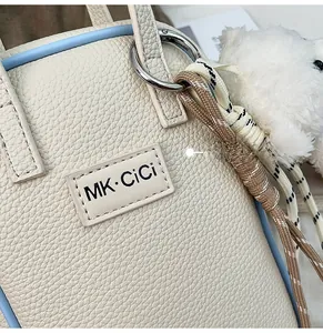 Vue rapprochée du sac en cuir grainé avec logo MK et charm ours en peluche