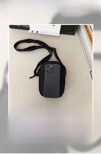 Detailed comparison showing compact nylon crossbody bag size next to a mobile phone