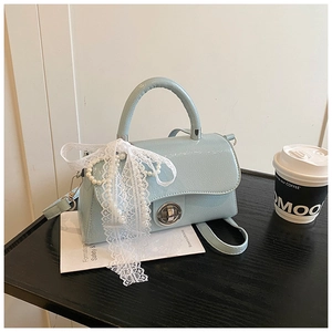Detail of light blue patent leather bag with lace ribbon, pearl chain and silver lock