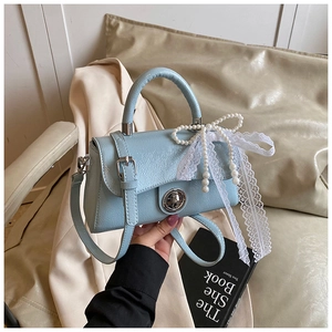 Detail of light blue PU leather bag with pearl bow decoration and white lace ribbons