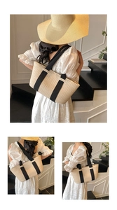 Detalle de un bolso tote de paja tejida beige con asas anchas de cinta negra para vacaciones