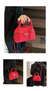 Detail view of red Boston bag with pebbled leather texture and golden metal accents