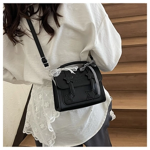 Detail of black crossbody bag featuring star patches and white lace trim with a bow