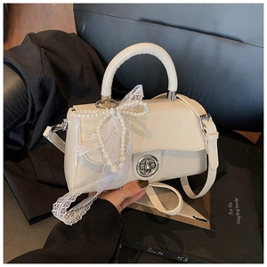 Detail of cream PU leather handbag featuring elegant pearl bow and delicate lace trim