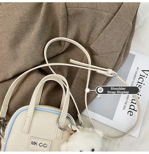 Détail du sac bandoulière en cuir grainé avec sangle réglable et pendentif ours