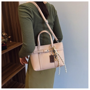 Detail of beige litchi grain leather bucket bag with creative charms and strap