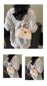 Detail of cream Boston handbag with golden hardware and textured leather displayed on model