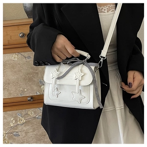 Close-up of a white leather crossbody bag with star patch and checkered ribbon detail