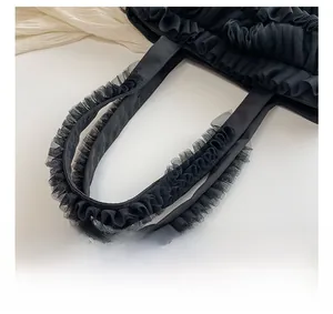 Gros plan d'un sac cabas noir avec bandoulière ornée de volants en tulle élégants