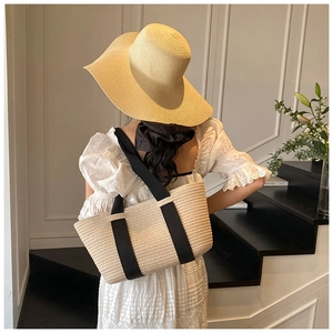 Bolso tote de paja con asas negras combinado con un vestido blanco para el verano