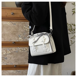 Detail view of a white PU leather crossbody bag with star patches and a checkered ribbon