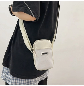 Detail of white mini crossbody phone bag with mesh pocket and silver zipper on model