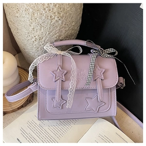 Detail of lavender star handbag with lace ribbon set against elegant lifestyle props