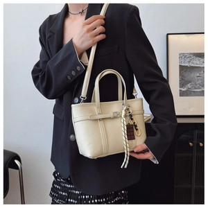 Detailed texture of beige lychee pattern bucket bag with chocolate charm and tassel