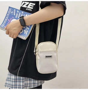 Detail view of mini cream nylon crossbody bag with mesh pocket and adjustable strap