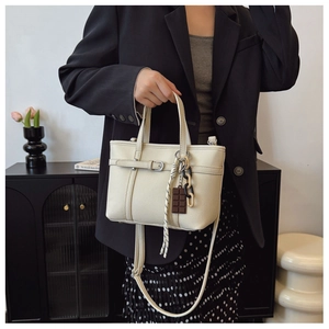 Chic beige bucket bag with litchi texture and a chocolate charm on a model